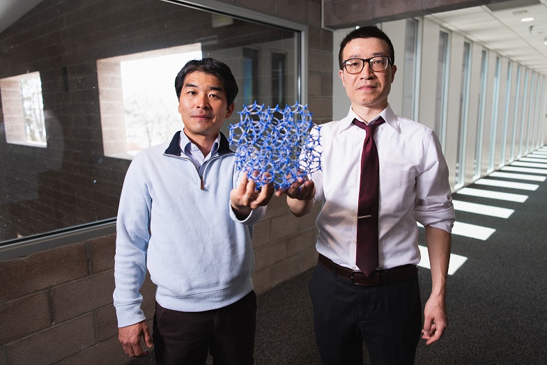 Experimentalist Hisato Yamaguchi, left, and Theoretical division theorist Gaoxue Wang, right, hold an atom structure model.